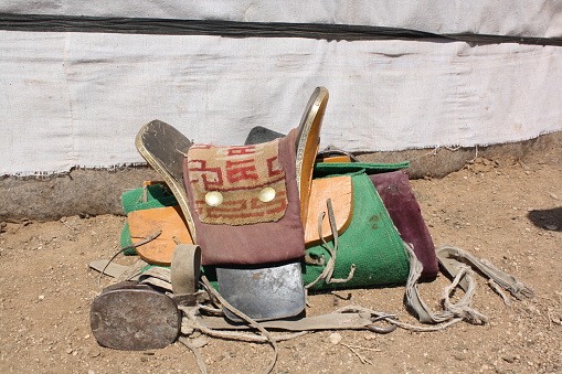 Mongol horse saddle by the nomadic tent (ger), Tuv, Mongolia. The horse saddle symbolically describes the Mongol nomadic values. The nomads carry out those values each day as seen the way they dress up.
