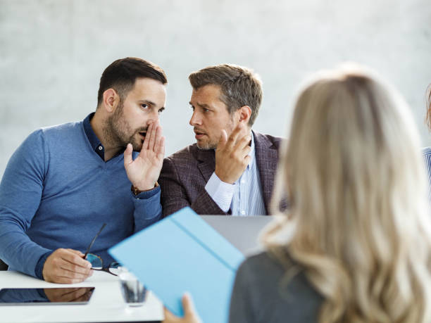 Whispering on a meeting in the office! Male members of human resource team gossiping during a job interview in the office. whisper men stock pictures, royalty-free photos & images