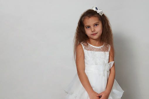 Cute girl portrait on a white background with copy space. 5 years old girl wearing white dress