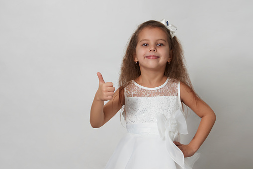 Cute girl portrait on a white background with copy space. 5 years old girl wearing white dress