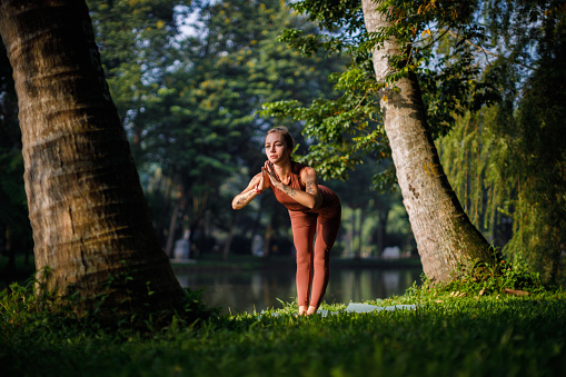 Beautiful blond girl doing morning yoga at the park next to the lake in Ba Dinh, Hanoi, Vietnam