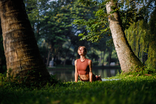 Beautiful blond girl doing morning yoga at the park next to the lake in Ba Dinh, Hanoi, Vietnam