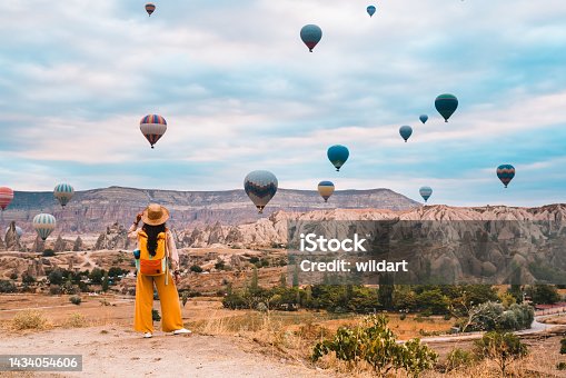 istock Traveler backpacker girl is watching hot air balloons and the fairy chimneys  at Cappadocia Goreme in Nevsehir , Turkey 1434054606