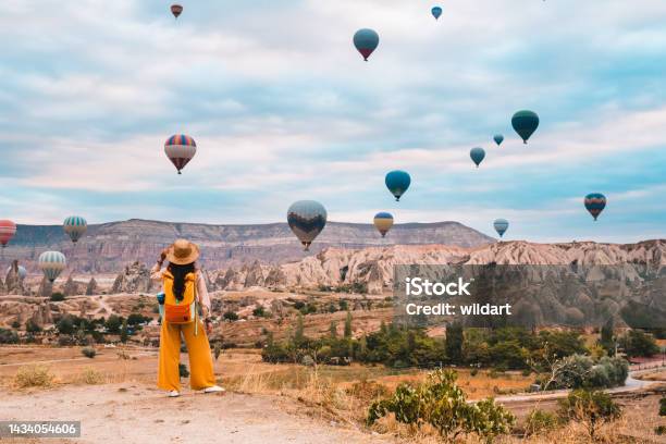 Traveler Backpacker Girl Is Watching Hot Air Balloons And The Fairy Chimneys At Cappadocia Goreme In Nevsehir Turkey Stock Photo - Download Image Now