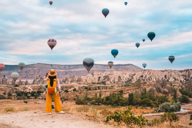 podróżna dziewczyna z plecakiem ogląda balony na ogrzane powietrze i bajkowe kominy w cappadocia goreme w nevsehir w turcji - travel zdjęcia i obrazy z banku zdjęć