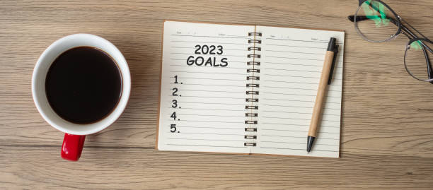 istock 2023 GOAL with notebook, black coffee cup and pen on wood table, Top view and copy space. Happy New Year, Resolution, To do list, Strategy and Plan concept 1434055362