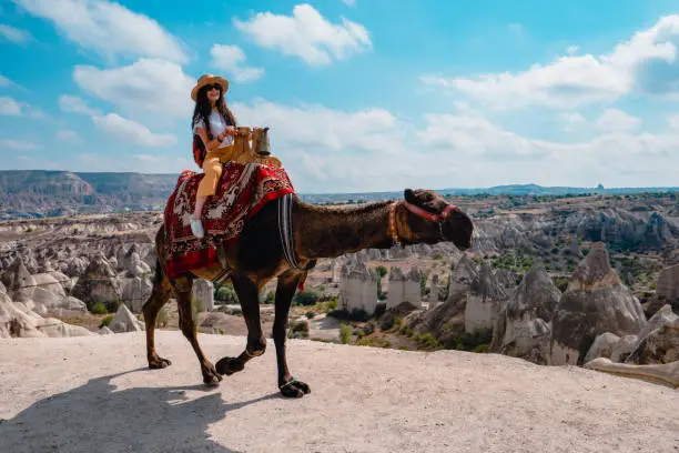 Photo of Traveler backpacker girl is riding a camel in Love Valley  at Cappadocia in Nevsehir , Turkey