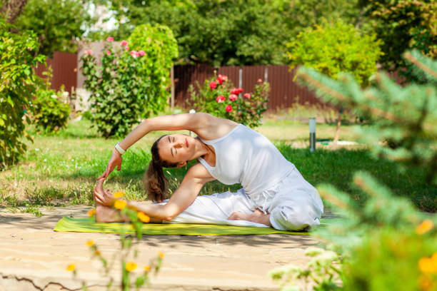 Young woman practices yoga in the summer garden - Inverted tilt of the head to the knee, parivritta Janu Shirshasana Young woman practices yoga in the summer garden - Inverted tilt of the head to the knee, parivritta Janu Shirshasana. shirshasana stock pictures, royalty-free photos & images