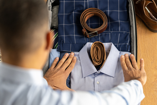 Overhead view of man packing clothes in his suitcase.