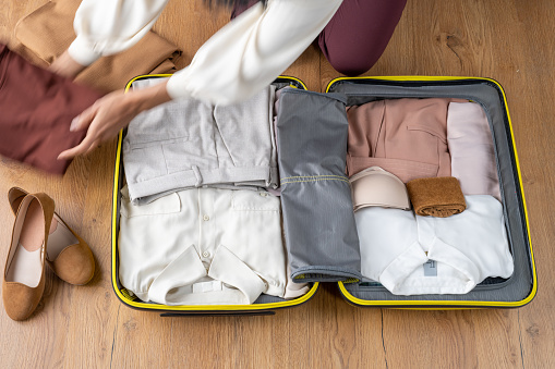 Elevated view of woman packing clothes in her suitcase.
