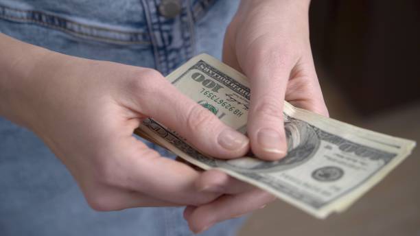 istock Close-up of female hands counting dollars 1434061910