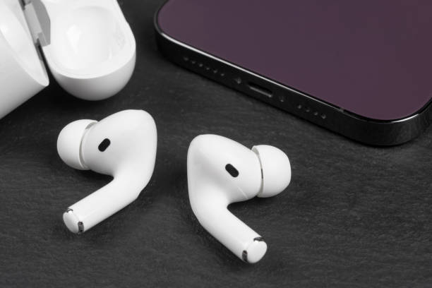 istock Modern wireless earbuds headphones with charging case iand smartphone on stone table background. Earphones for smartphone and tablet 1434063457
