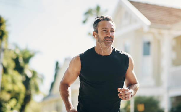 coureur, fitness et homme senior en train de courir, écouter de la musique en plein air dans le quartier pour le bien-être de l’entraînement, l’énergie et la motivation de mode de vie sain. sportif avec objectif d’entraînement physique dans la r - only senior men audio photos et images de collection