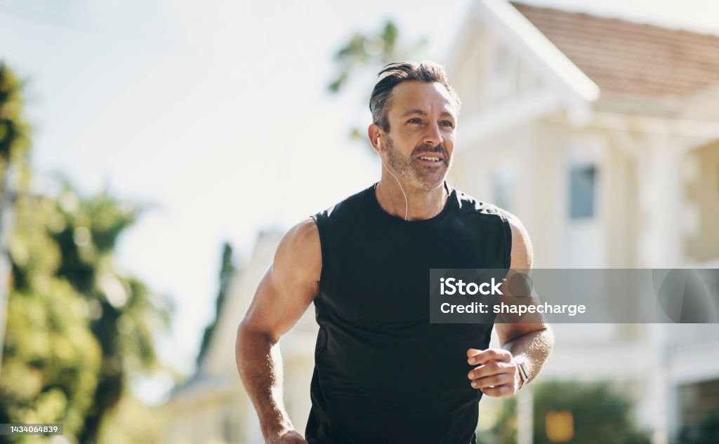 Runner, fitness and senior man running, listening to music outdoor in neighborhood for workout wellness, energy and healthy lifestyle motivation. Sports person with exercise training goal in street Men Stock Photo
