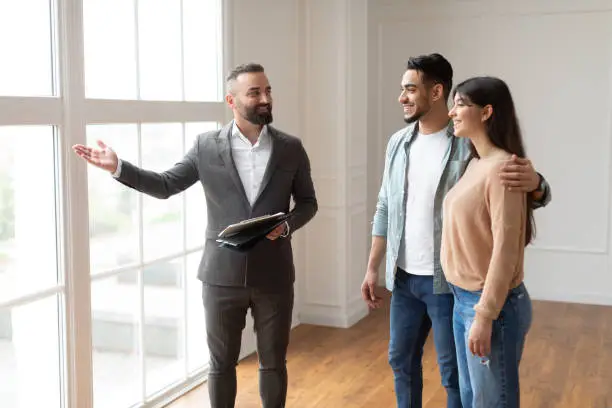 Photo of Estate Agent In Suit Showing Buyers New Apartment