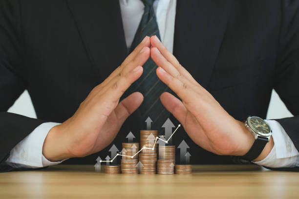 Businessman hands covering a stack of golden coins with stock market graph and up arrow.Money Protection From Inflation.Inflation and interest rates increasing concept. Global financial crisis. Businessman hands covering a stack of golden coins with stock market graph and up arrow.Money Protection From Inflation.Inflation and interest rates increasing concept. Global financial crisis. recession protection stock pictures, royalty-free photos & images