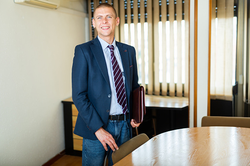 Positive experienced american businessman with briefcase standing in the office