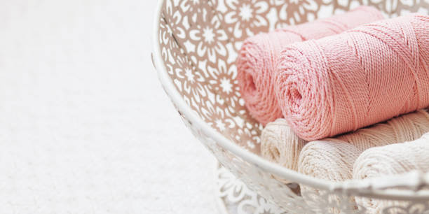 istock Handmade macrame braiding and cotton threads in white basket. Cotton macrame cords and ropes against wire basket. Good image for macrame and handicrafts banners and advertisement. Close up 1434071138