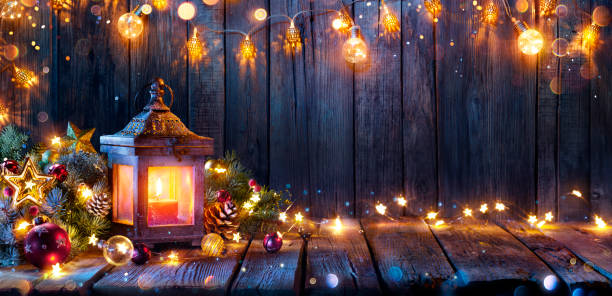 istock Christmas Lantern Glowing On Wooden Table With Decoration And String Lights 1434071185