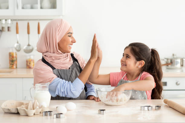 istock Happy Muslim Mom And Daughter Giving High Five While Baking In Kitchen 1434072717
