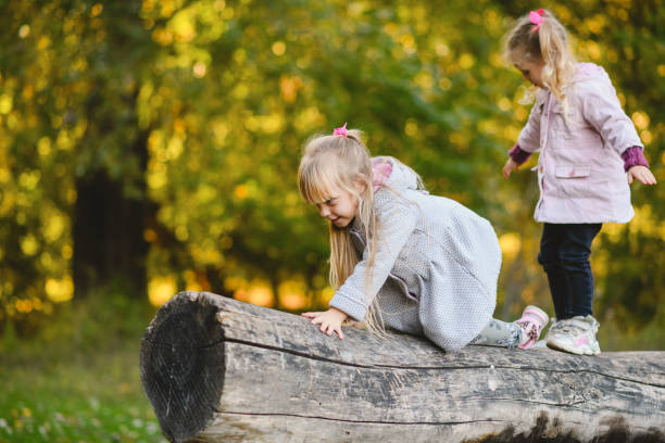 istock Two cute children climb, balance on a fallen log in an park. 1434073450