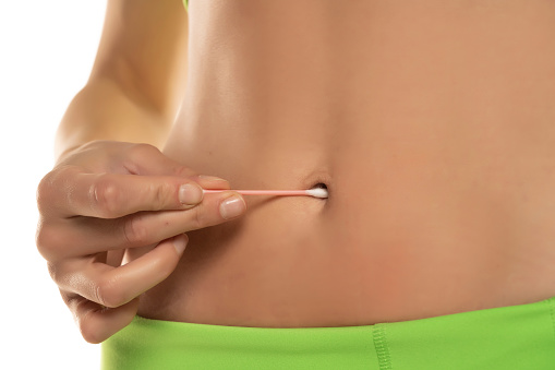 Woman cleaning her belly button with cotton swab , Cropped image, close up.