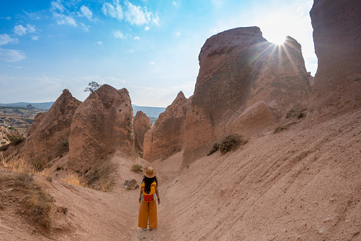 Traveler backpacker girl  is walking between the fairy chimneys in Red and Rose Valley  at Cappadocia in Nevsehir , Turkey