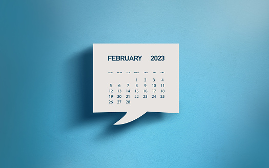 White Chat Bubble With Cut Out February 2023 Calendar Page Over Blue Background