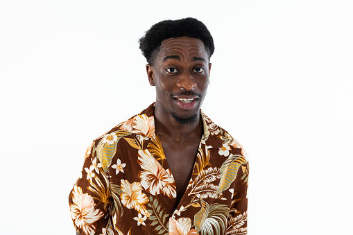 Curious african american man looking at camera surprised talking wearing colorful shirt standing n white background isolated in studio.