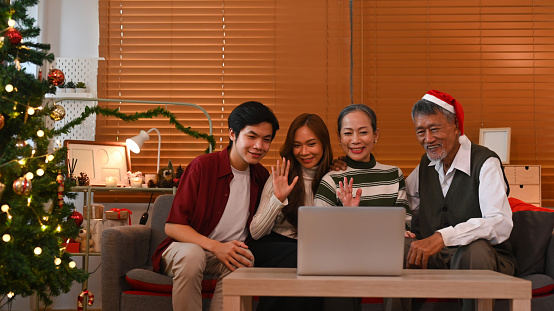 Joyful group of people having a video call on laptop, congratulating relatives during Christmas or New year holidays.