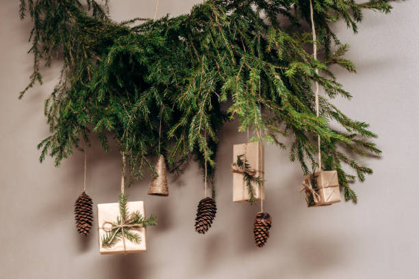 Christmas decor on the wall.Fir branches decorated with gift boxes in craft paper and fir cones.Eco-friendly concept.New Year and Christmas concept. stock photo