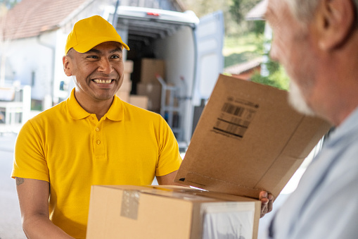 Smiling delivery man delivering packages to senior customer.