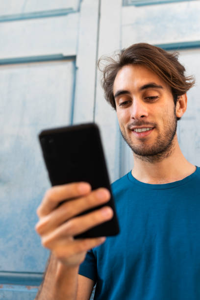 istock Vertical portrait of young caucasian man using mobile phone browsing social media. Selective focus on face. 1434091076