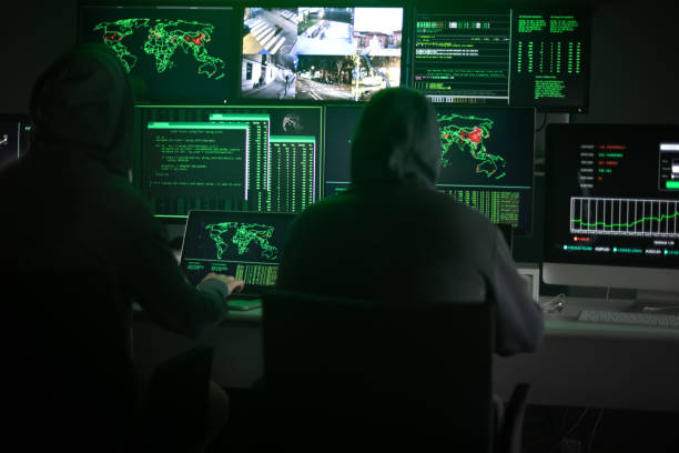 istock Two hooded hackers hacking security firewall late at night in basement hideout 1434091117