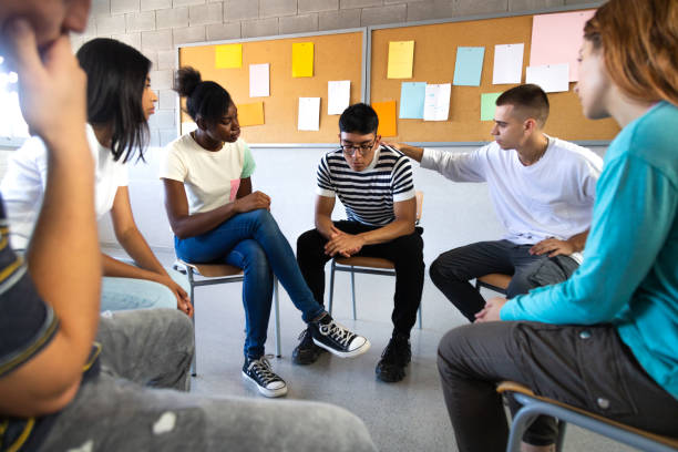 Sad hispanic male high school student sharing bad news with classmates. Multiracial teenagers sitting in circle in Sad hispanic male high school student sharing bad news with classmates. Multiracial teenagers sitting in circle in class comfort depressed teen boy. Mental health and education concepts. group talking school stock pictures, royalty-free photos & images