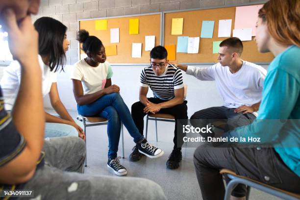 Sad Hispanic Male High School Student Sharing Bad News With Classmates Multiracial Teenagers Sitting In Circle In Stock Photo - Download Image Now