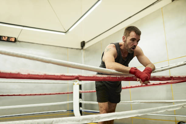измученный боксер восстанавливается на ринге боя после напряженного боксерского спарринга в тренажерном зале в буэнос-айресе - boxing ring фотографии стоковые фото и изображения