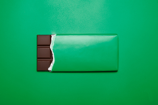 opened bar of chocolate on green background