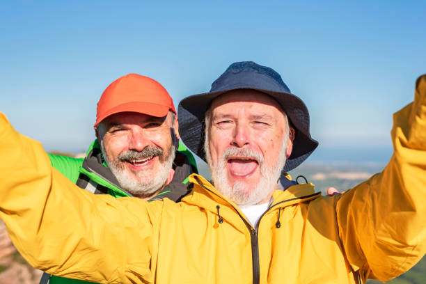amigos mayores felices tomándose selfies mientras caminan juntos - 50 days old fotografías e imágenes de stock
