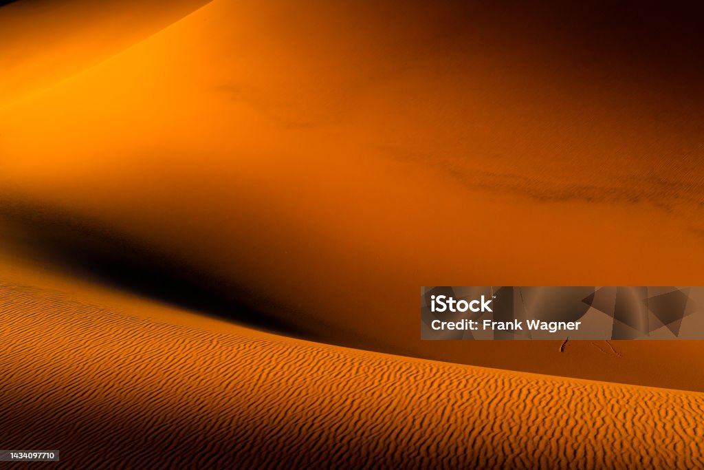 Sandwüste Orange in the evening sunlight glowing curved sand dunes with undulating hills and valleys Arid Climate Stock Photo