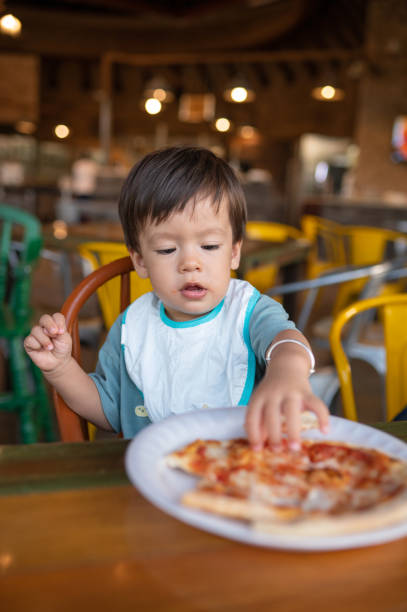 istock Infant baby boy having pizza in the restaurant using his hands alone 1434098019