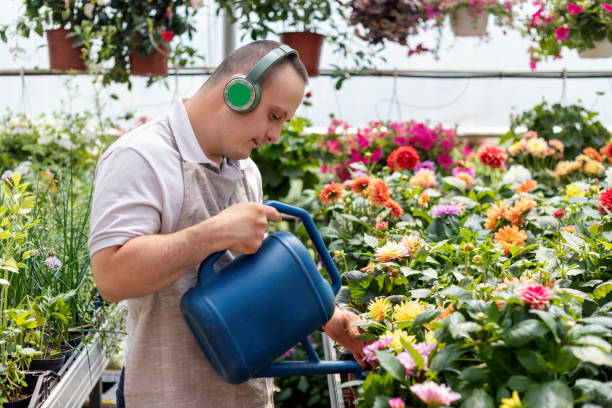 Social inclusion - man with down syndrome working in garden center stock photo