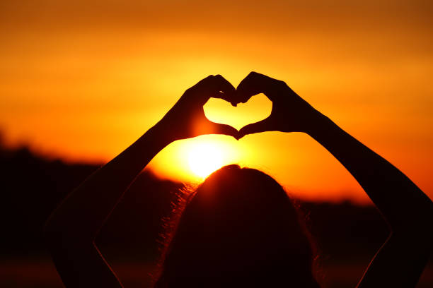 istock Woman hands doing heart shape at sunset or sunrise 1434103868