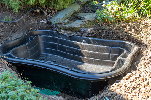 A preformed pond liner being installed in a garden.