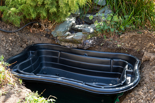 A preformed pond liner being installed in a garden