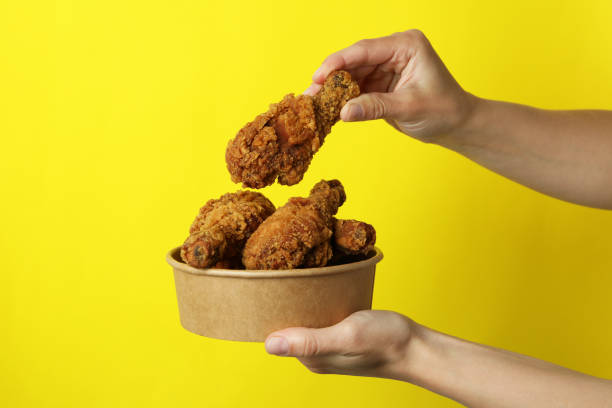 istock Female hands hold fried chicken on yellow background 1434105228