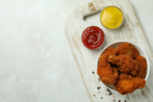 Concept of tasty eating with fried chicken on white textured table