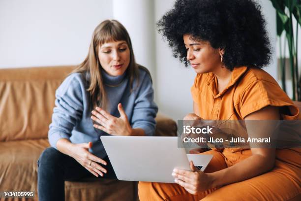 Two Businesswomen Having A Discussion While Looking At A Laptop Screen Stock Photo - Download Image Now