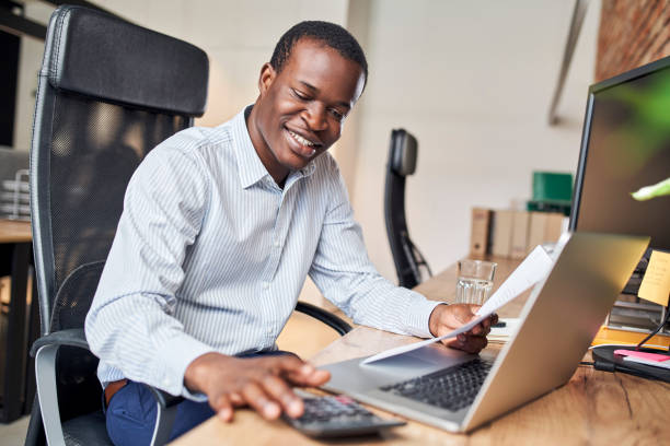 Smiling businessman calculating business income doing paperwork in office