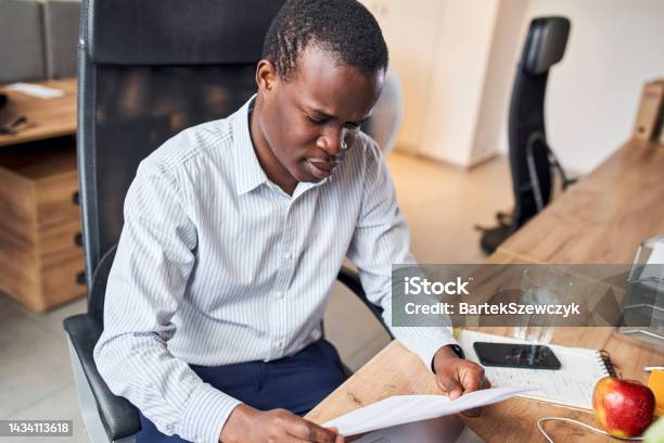 Young focused businessman in office reading document